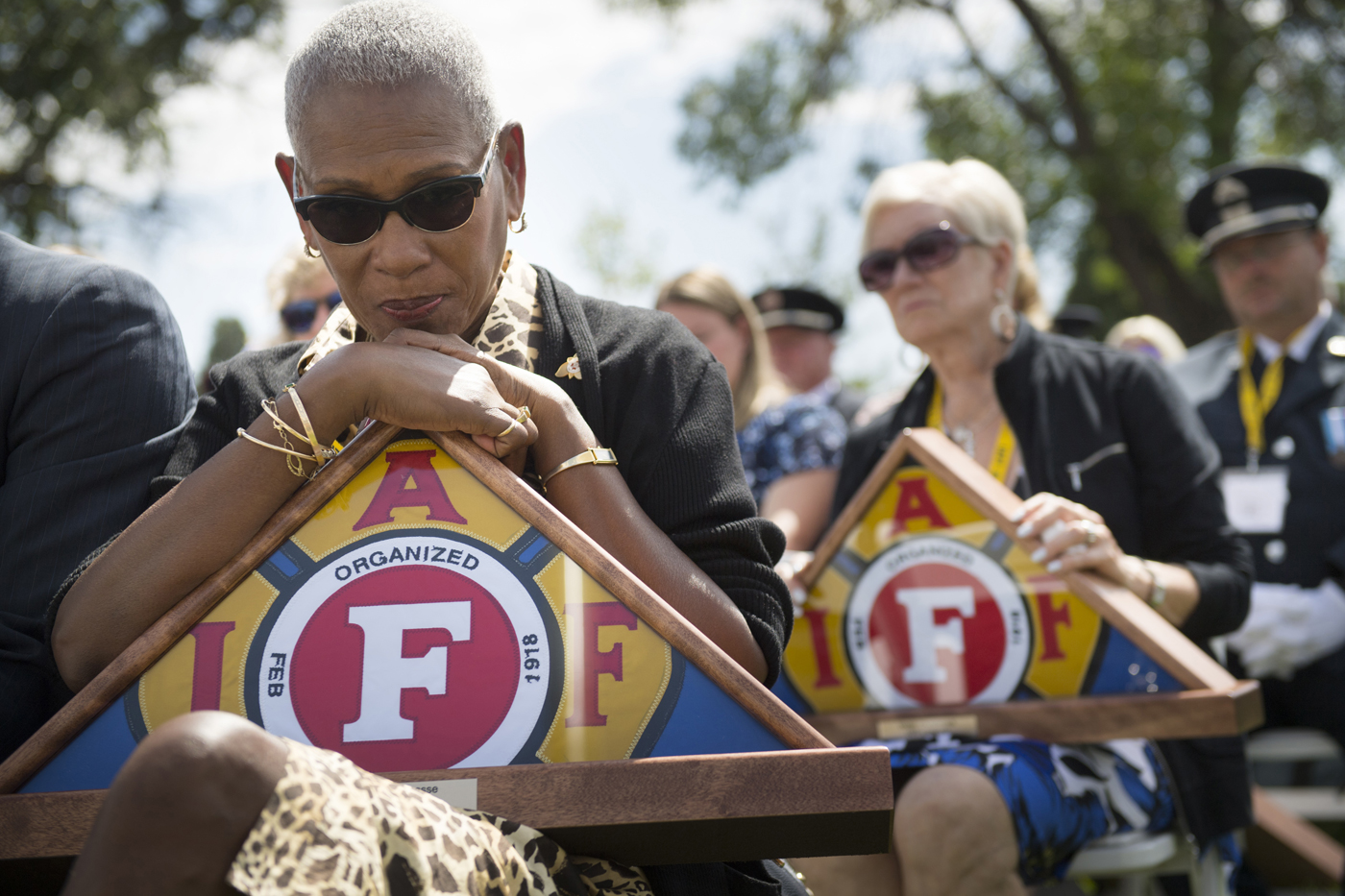 Lucille Lacasse of Mississauga, Ontario rests her chin on a memorial flag presented to her to honor her husband during a ceremony for fallen firefighters. Her husband died in 2016 of work-related cancer. | Mark Reis