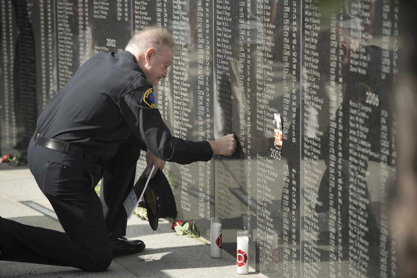 California firefighter Tim Gilligan touches the name of his friend, fallen firefighter Daniel Bendiksen, on a memorial wal. Bendiksen died in 2003 of work-related cancer. | Mark Reis